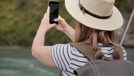 vista de mano de una turista con un teléfono móvil fotografiando el paisaje