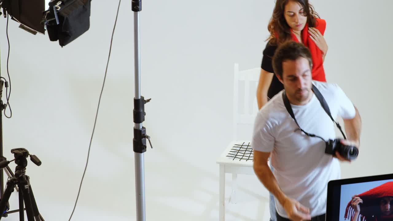 fotógrafo masculino mostrando fotos a un modelo femenino en una computadora 4k