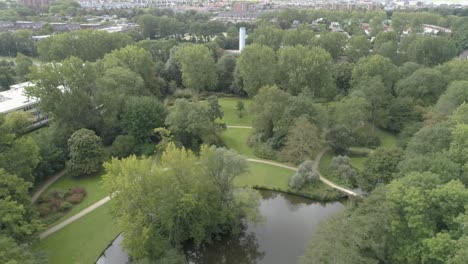 aerial overview slowmotion of a small dutch park during spring with a pond and paths surrounded by trees