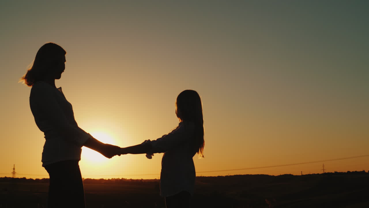 mamá sostiene las manos de su hija solas al atardecer concepto de madre soltera video 4k