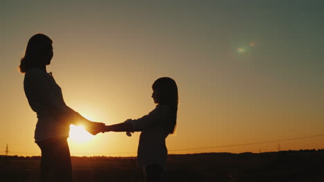 mom holds her daughter's hands stand alone at sunset single parent concept 4k video