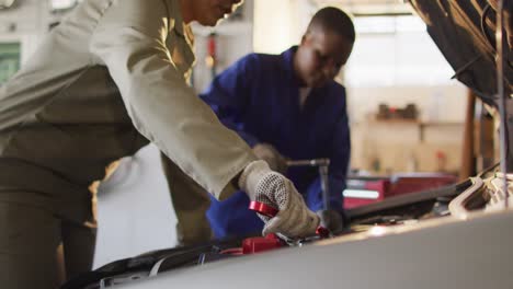 video of midsection of two diverse female car mechanics repairing car