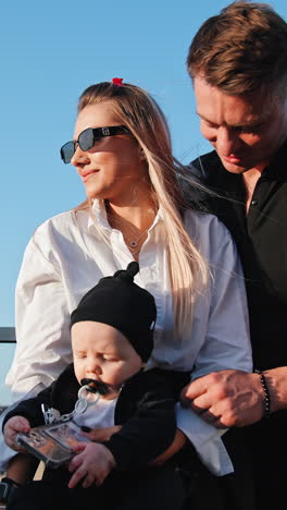 beautiful caucasian couple with their adorable newborn. happy family of three outdoors. low angle view. vertical video