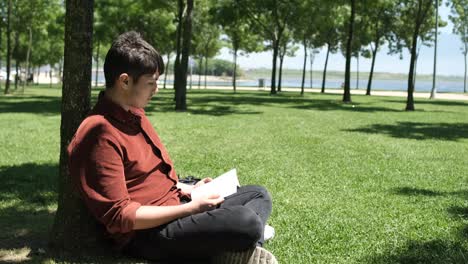 man reading book in grass