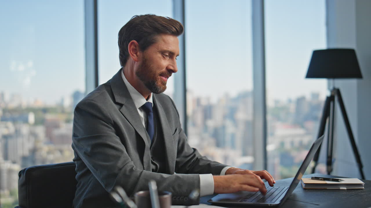 el jefe sonriente hablando en la red de portátiles en línea. el gerente tranquilo bebiendo café