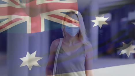 Animation-of-flag-of-australia-waving-over-caucasian-woman-wearing-face-mask-in-city-street