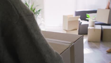 Caucasian-lesbian-couple-moving-cardboard-boxes-in-living-room-in-new-home