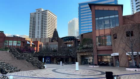 Empty-urban-plaza-with-modern-buildings,-clear-blue-sky,-and-a-lone-bicycle,-shot-in-daylight