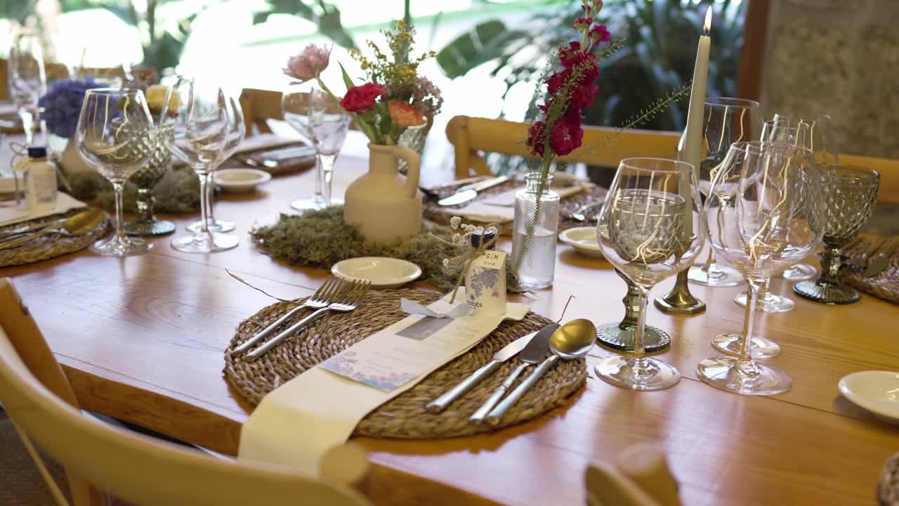 Charming boho wedding table with floral vases, glassware, and woven placemats