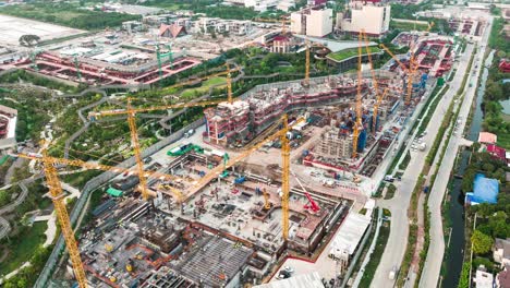 hyperlapse time-lapse of under construction site project, crane transportation at night in asia city. drone aerial view. industrial business or civil engineering technology concept