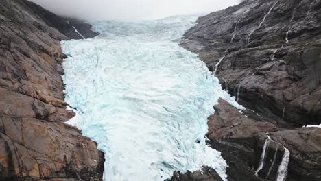 a-huge-glacier-between-the-rocks-of-a-mountain,-Briksdalsbreen,-norway,-nature,-drone