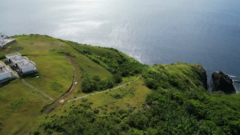 orbiting aerial view of cliffside island resort with lush greenery and turquoise ocean bay in catanduanes, philippines