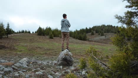 Video-of-a-young-man-standing-by-himself-in-a-calm,-natural-forest-setting,-looking-sad-and-lonely