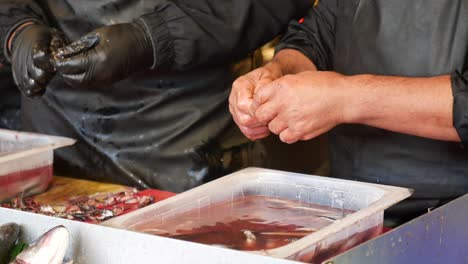 fisherman cleaning and preparing fresh fish at a market