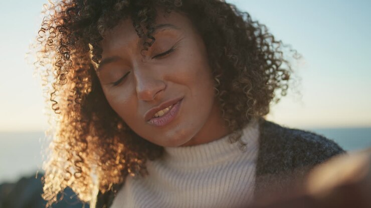 Cheerful woman talking sunset light at sea horizon closeup. Curly model laughing