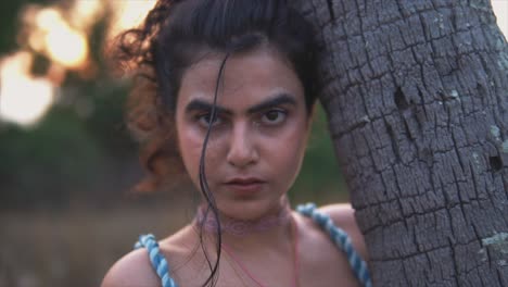 self-confident, beautiful lovely woman holding a palm tree and looking into camera