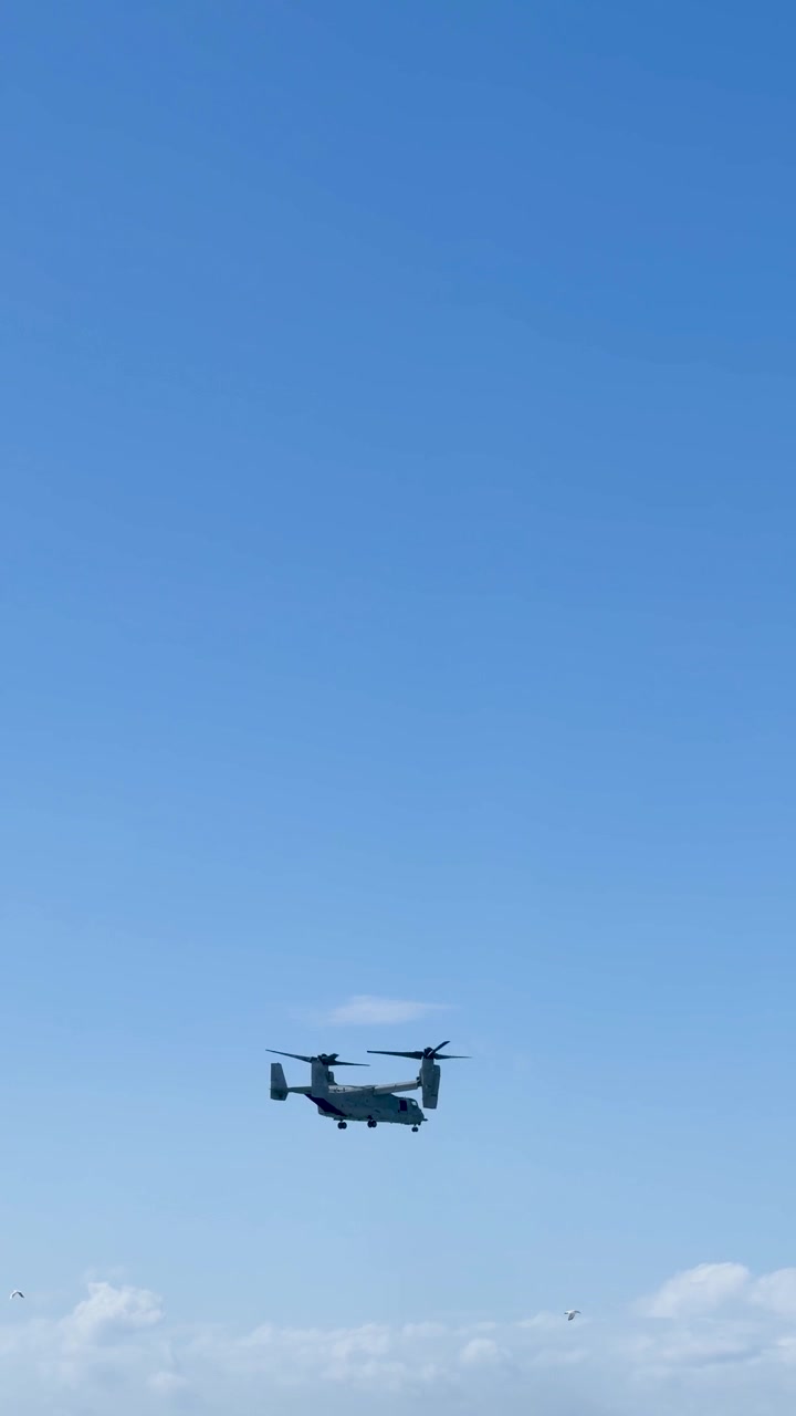 A military tiltrotor aircraft performs a flight demonstration against a clear blue sky in Queensland.