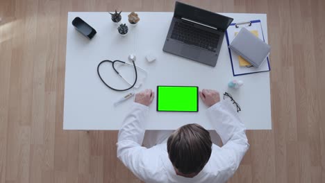 médico de cabecera viendo un video médico en una tableta con pantalla verde