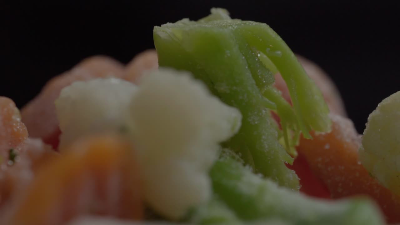 Extreme close-up detail of frozen broccoli, carrots, and cauliflower showing frosty textures