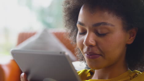 Primer-Plano-De-Una-Mujer-Relajándose-En-El-Sofá-De-Casa-Usando-Una-Tableta-Digital-Para-Transmitir-Películas