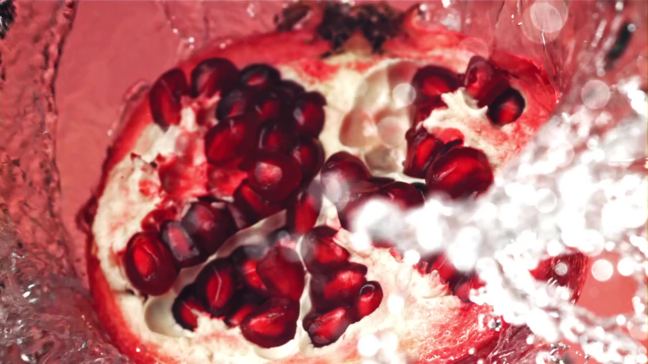 Slowmotion vand sprøjter på et frisk halvt granatæble