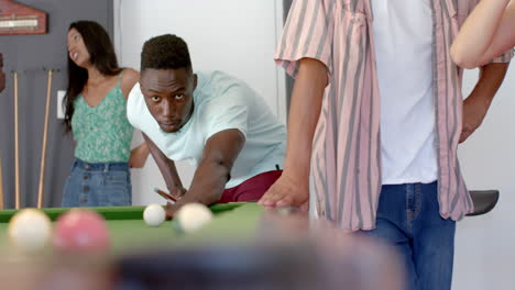 young african american man plays pool at a casual indoor gathering