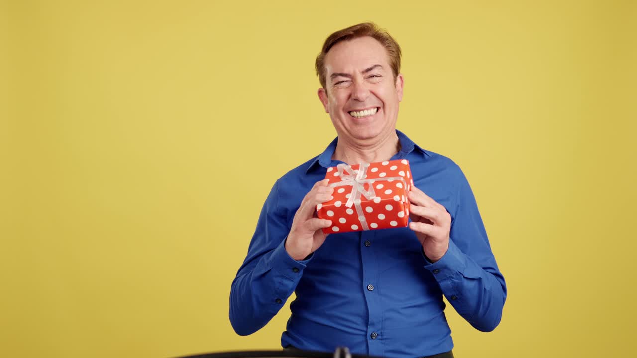 Happy Man with a Gift Box on Yellow Background