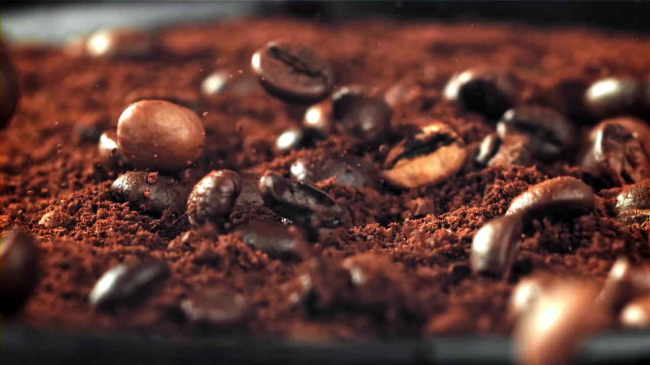 Ristede kaffebønner falder ned på malet kaffe i slowmotion