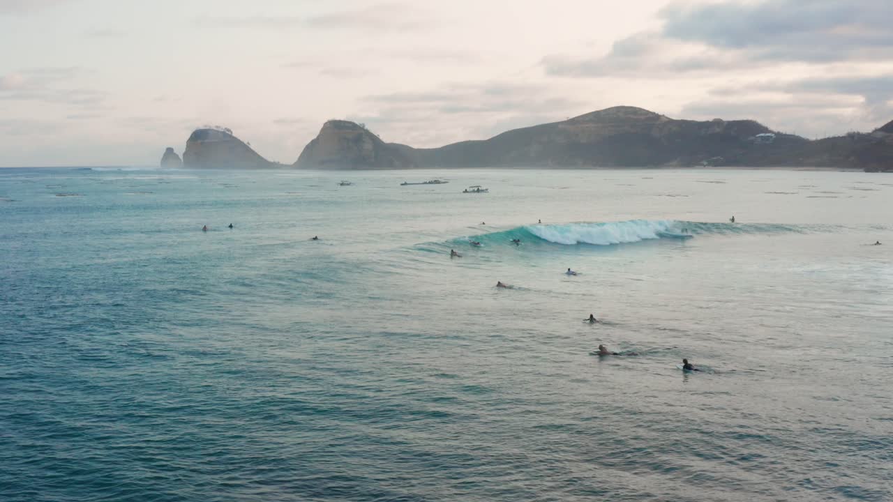 Surfování při západu slunce na surfovém spotu Don Don v Gerupuku, Lombok.