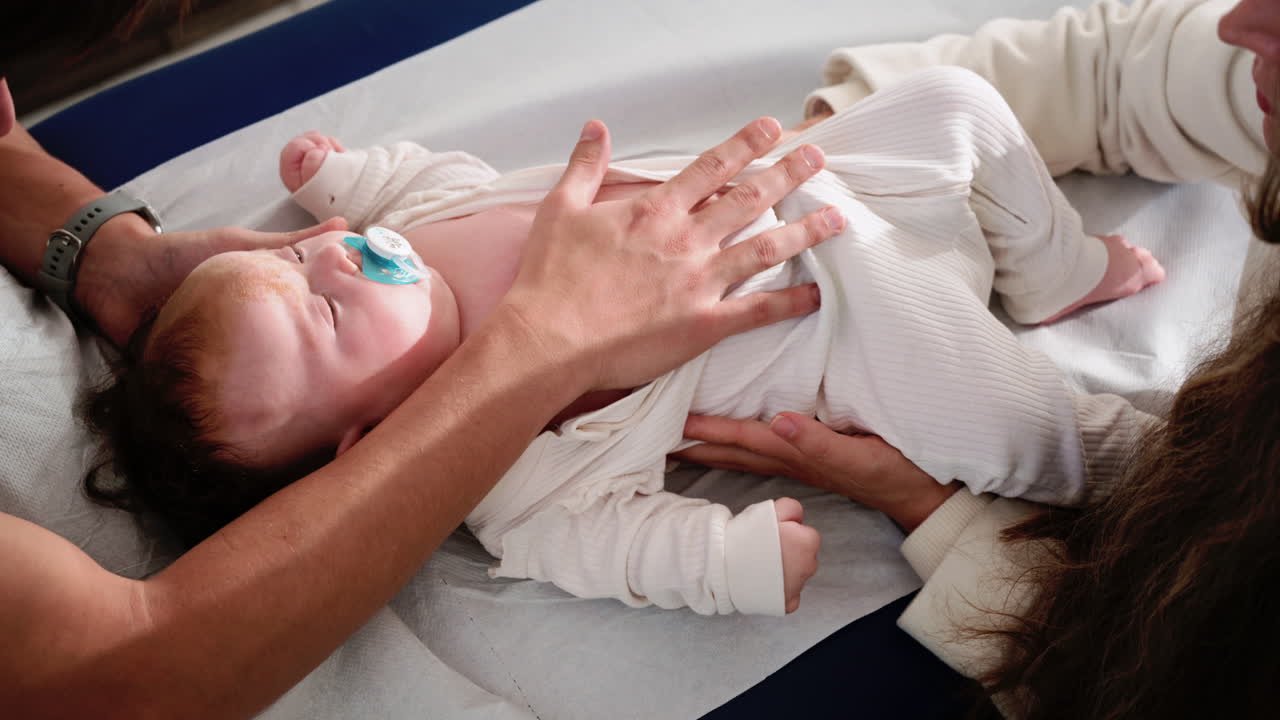 Neonato sdraiato e rilassato, sostenuto dalle mani dei genitori