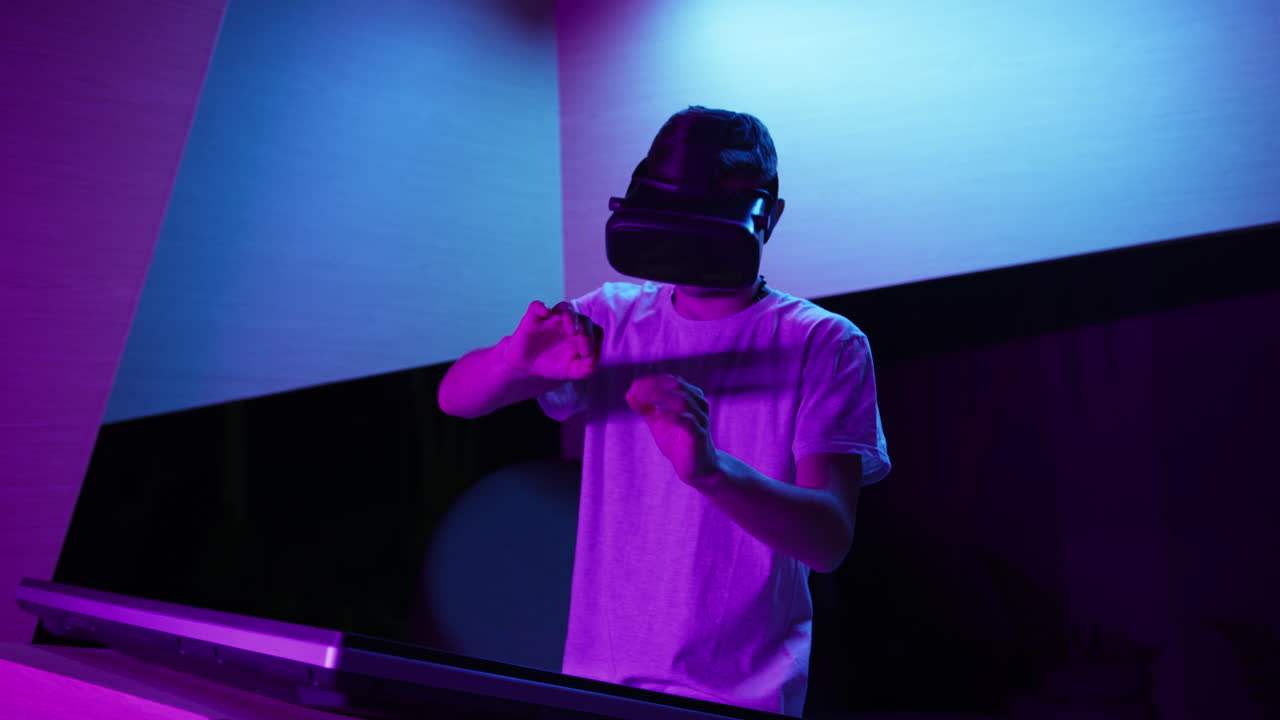 Giovane uomo con visore VR in piedi che fa gesti con le mani in aria, vista frontale