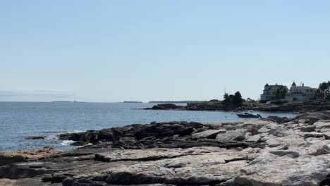 Boothbay-Harbor-Coastline,-static-shot,-boat-moored-in-bay,-vacation-homes-on-the-peninsula,-islands-in-the-distance