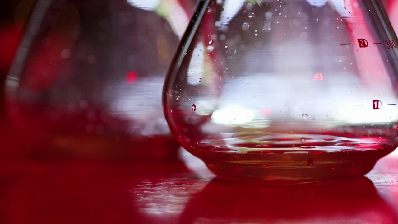 Close-up of liquid drop entering cocktail glass, vibrant lighting, shallow focus, static camera angle