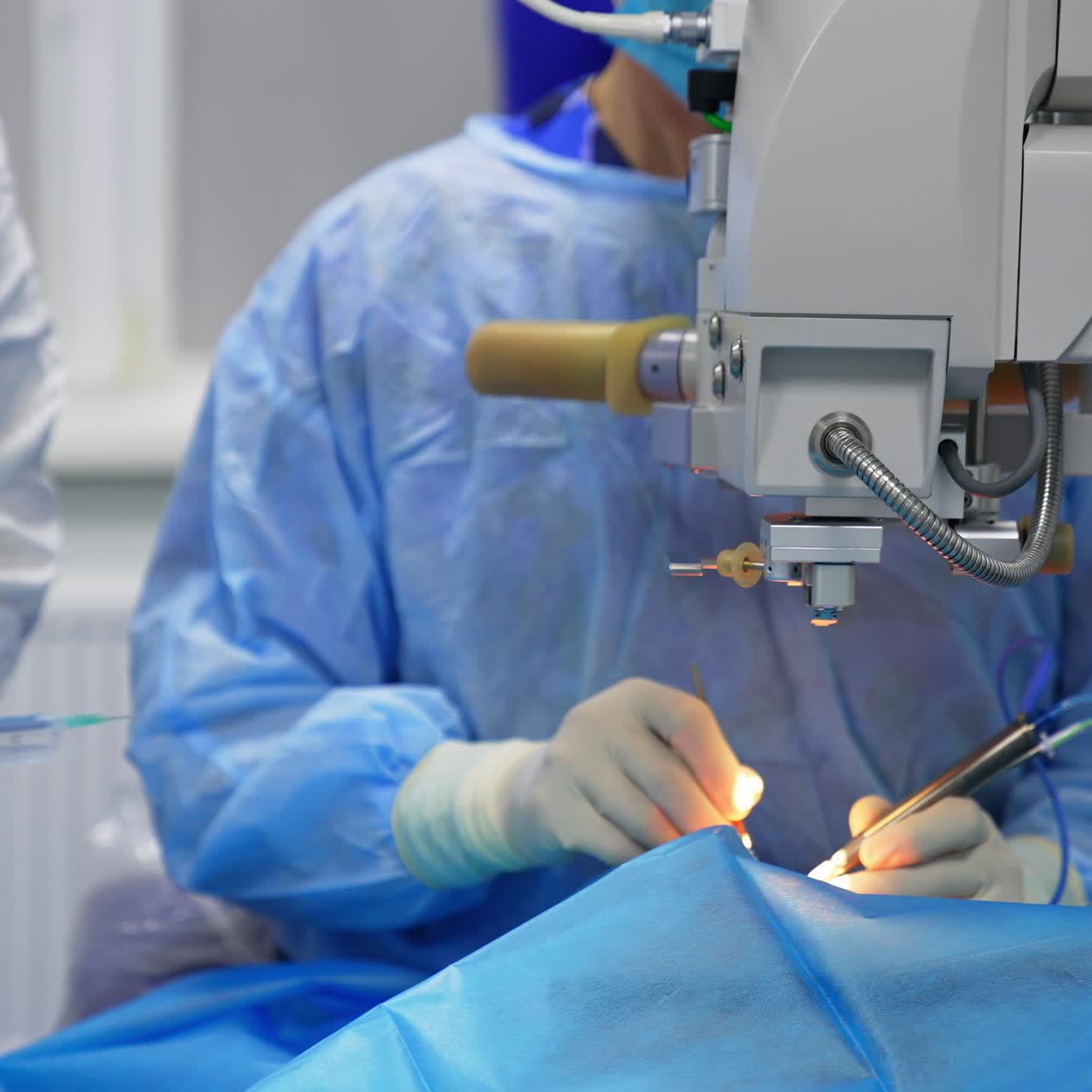 Chief surgeon conducting eye surgery using electric devices. Nurse sprinkles the medicines from syringe on patient's eye