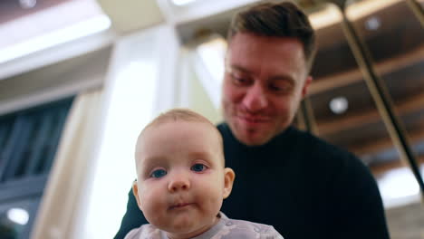 happy smiling caucasian man holding a little boy. father in black sweater puts his infant son on the shoulder. low angle view.