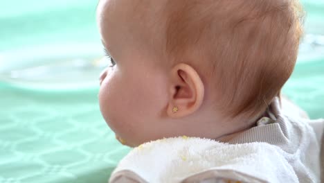 a curious baby wearing a bib stares into the camera and then turns its head, slow motion shot