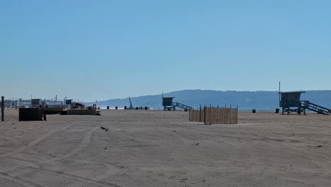 Still-landscape-shot-of-Venice-Beach-coastline-with-sand-and-background-headland-lifeguard-tower-huts-holiday-travel-destination-Los-Angeles-America-USA