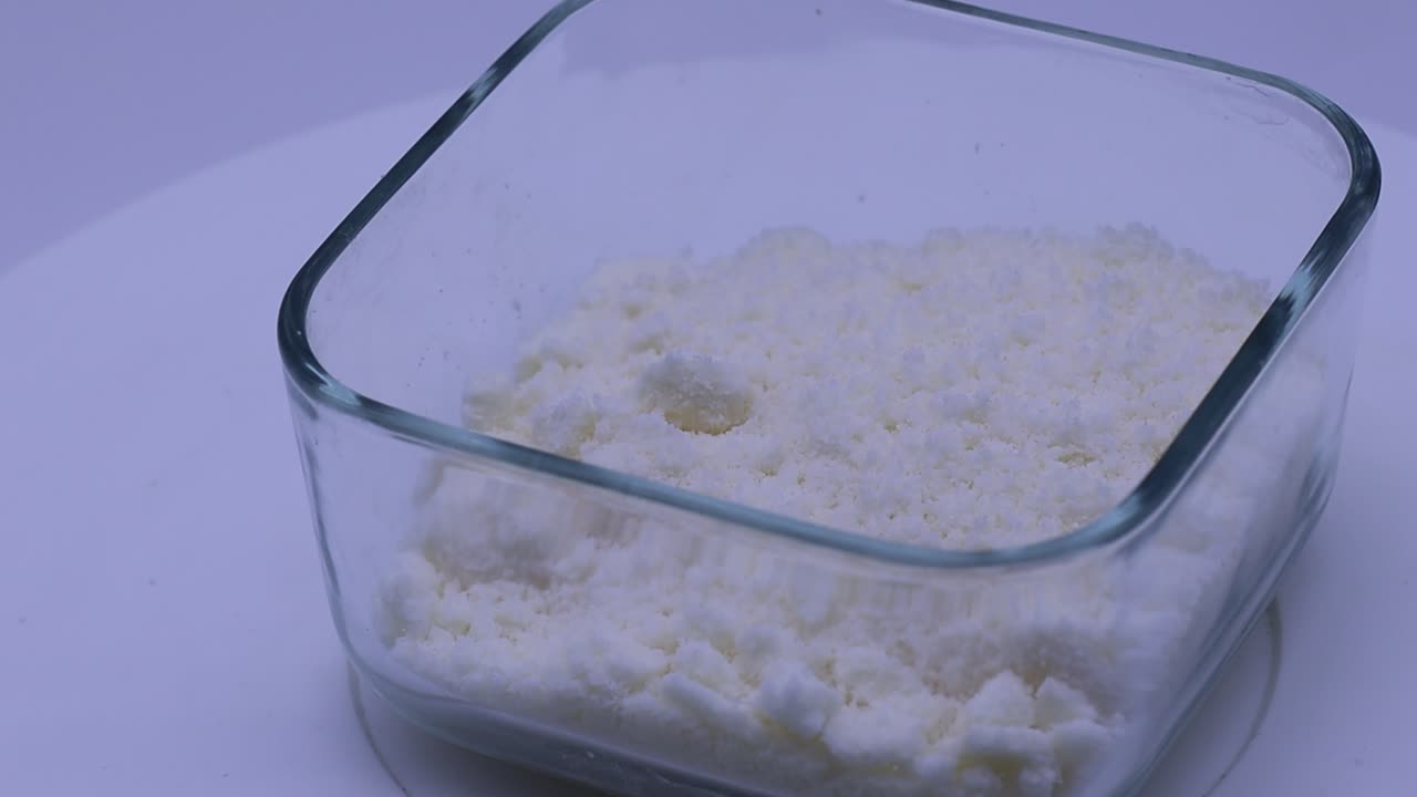Grated Italian Pecorino cheese in a glass bowl on a kitchen table