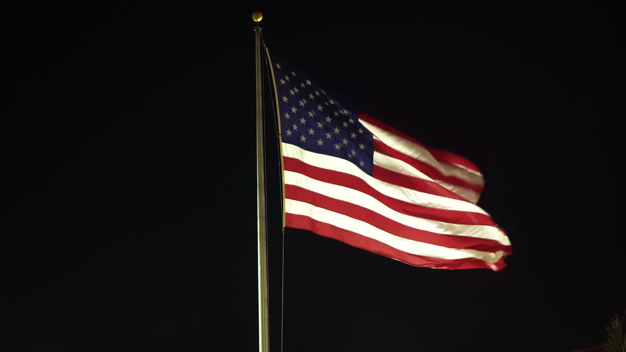A United States flag wavering on a cold windy night in slow motion.