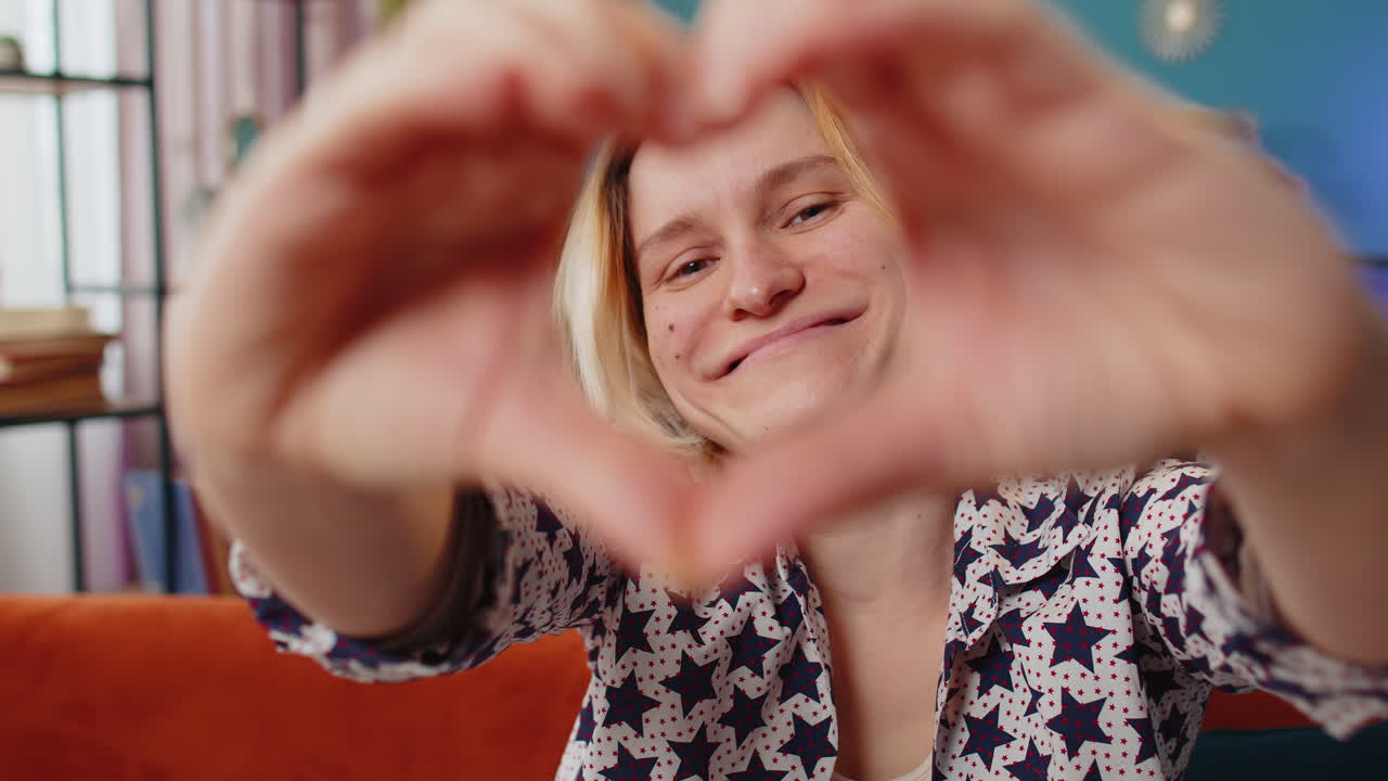 Portrait of happy caucasian young woman makes symbol of love showing heart sign romantic feelings