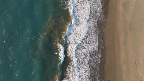 top down drone shot over waves at the limni beach, sunset in rhodes, greece