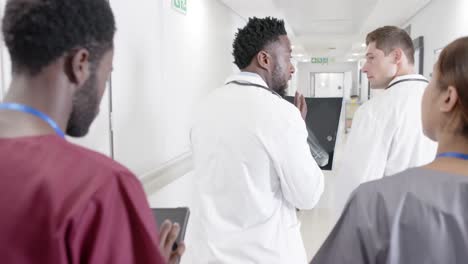 serious diverse male and female doctors talking and walking with x ray in slow motion, unaltered