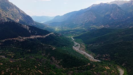 sweeping aerial of alpine ridge with forested slopes and distant snow capped mountains