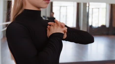 blonde woman in black top posing her hands in a dance studio