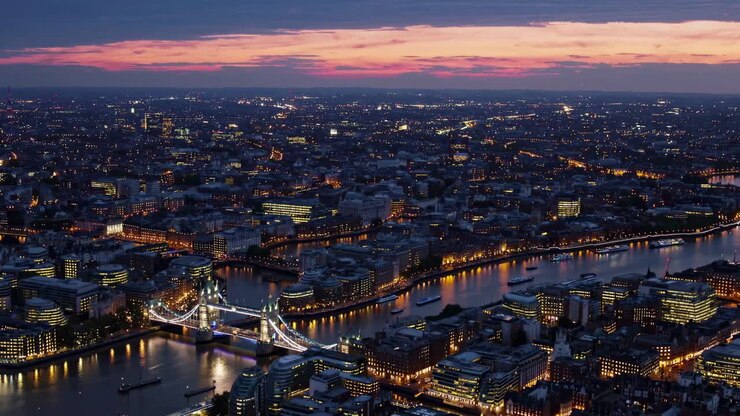 Luchtopname van een stadsgezicht bij zonsondergang, met verlichte bruggen en gebouwen.