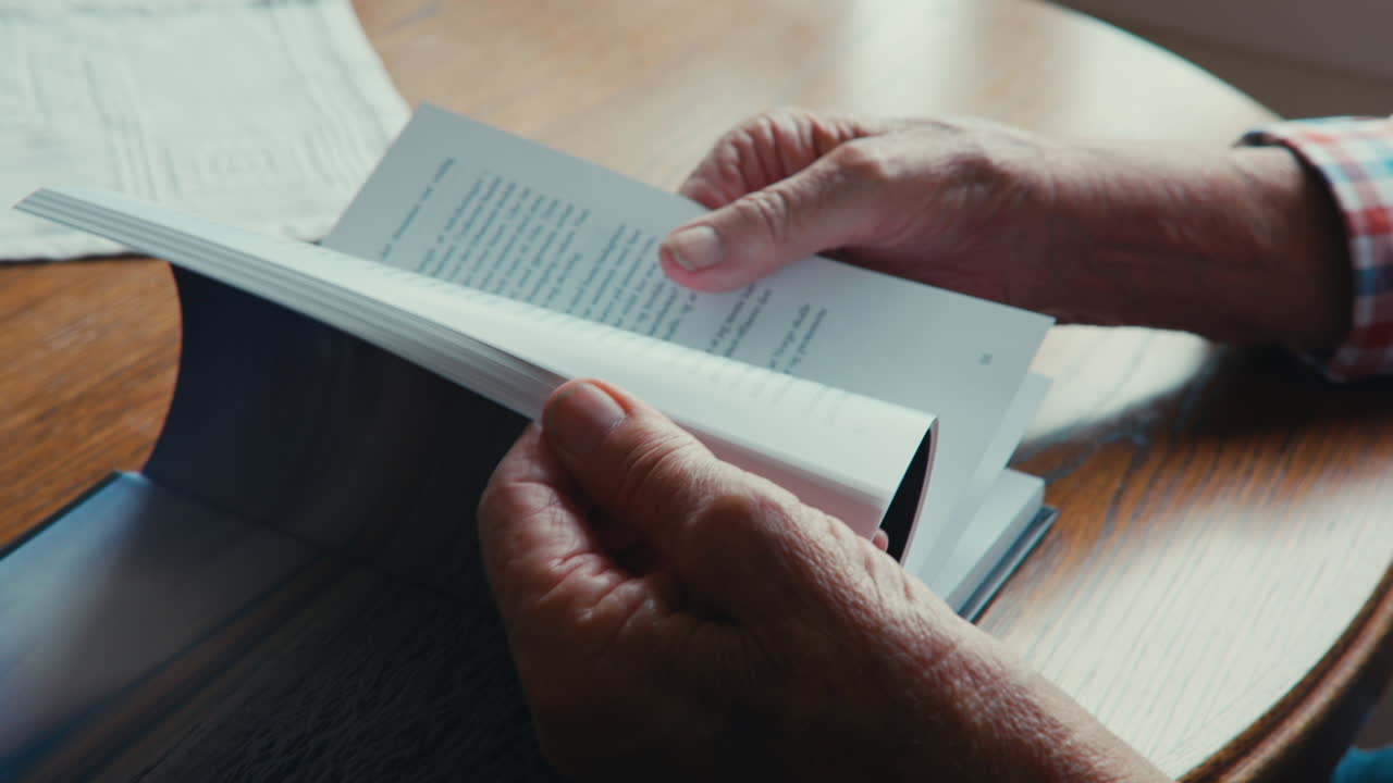 Old mans wrinkled hands turning pages of book
