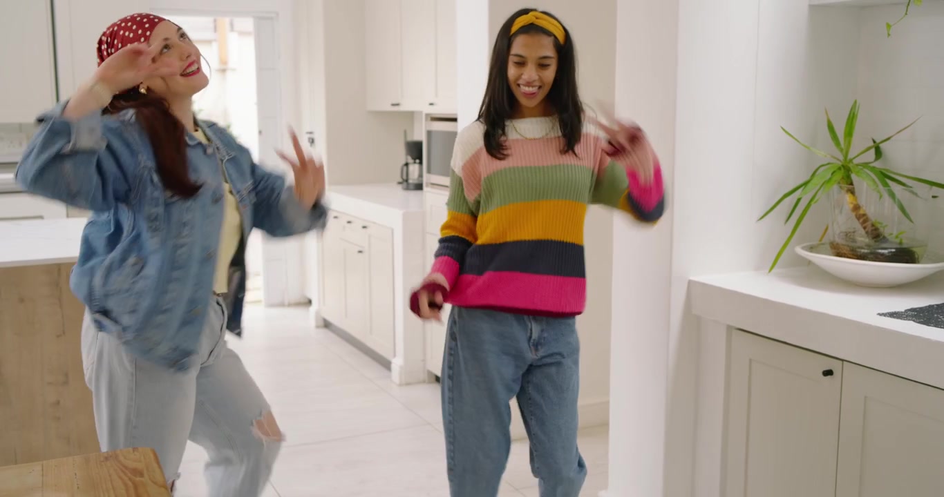 Diverse women friends placing vinyl on turntable at console, starting music and dancing in hallway