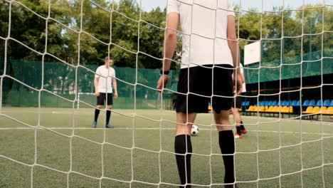 goalkeeper trying to defend the goal while attacking team creating opportunity to score a goal during football training match on soccer pitch