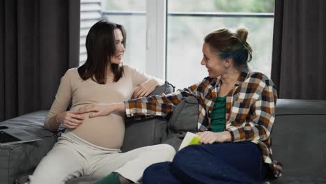 woman touching pregnant belly, feeling baby movement, friendship closeness