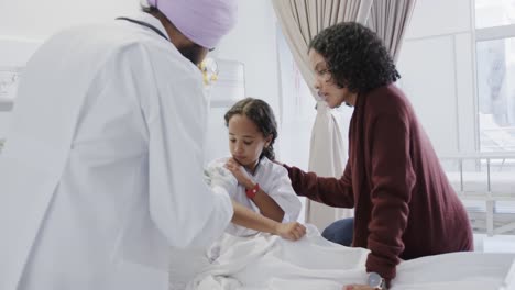 biracial doctor vaccinating sick girl patient with mother in hospital in slow motion